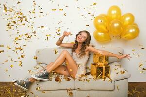 bonito mujer celebrando fiesta en dorado papel picado foto