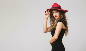 joven hermosa elegante mujer en negro vestido, rojo sombrero foto