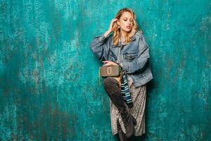 attractive stylish blonde woman in jeans oversize jacket walking against wall fashion photo