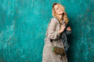attractive stylish blonde woman in jeans oversize jacket walking against wall fashion photo