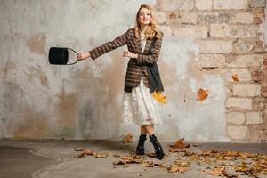 attractive stylish blonde woman in checkered jacket coat walking, autumn fashion trend photo