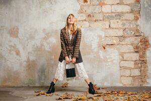 attractive stylish blonde woman in checkered jacket coat walking, autumn fashion trend photo