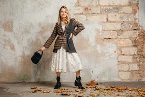 attractive stylish blonde woman in checkered jacket coat walking, autumn fashion trend photo