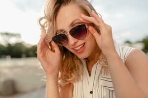 close-up portrait of young attractive stylish blonde woman in city street in summer fashion style photo