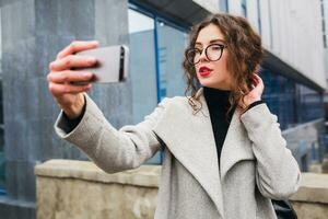 young beautiful woman walking in the city street in grey coat photo