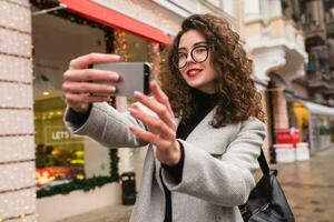 young beautiful woman walking in the city street in grey coat photo