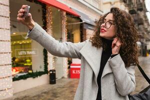 young beautiful woman walking in the city street in grey coat photo