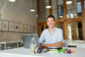 happy young confident man working on laptop photo