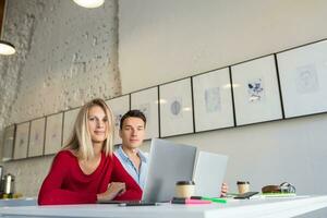 young man and woman working on laptop in open space co-working office room, busy freelancers photo