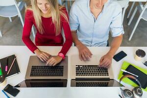 young man and woman working on laptop in open space co-working office room, busy freelancers photo