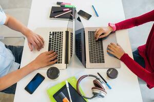 young man and woman working on laptop in open space co-working office room, busy freelancers photo