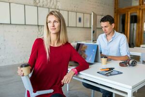 young man and woman working on laptop in open space co-working office room, busy freelancers photo