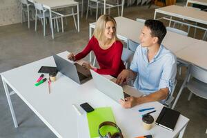 young man and woman working on laptop in open space co-working office room, busy freelancers photo