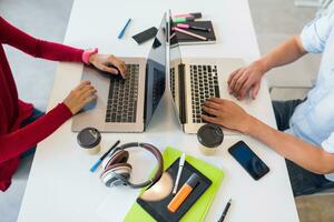 young man and woman working on laptop in open space co-working office room, busy freelancers photo