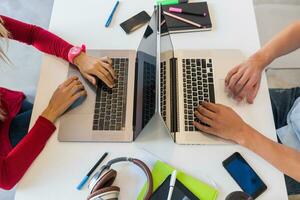 young man and woman working on laptop in open space co-working office room, busy freelancers photo