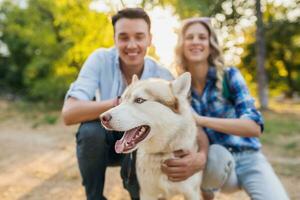 gracioso joven elegante Pareja jugando con perro en parque foto