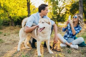 gracioso joven elegante Pareja jugando con perro en parque foto