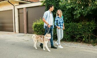 young stylish couple walking with dog in street, man and woman happy together photo