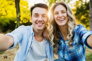 kissing young stylish couple sitting in park photo