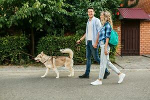 young stylish couple walking with dog in street, man and woman happy together photo