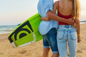 young couple having fun on beach walking with surf board photo