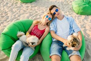 young attractive smiling couple having fun on beach playing with dogs photo