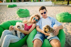 young attractive smiling couple having fun on beach playing with dogs photo