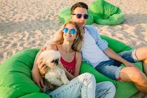 young attractive smiling couple having fun on beach playing with dogs photo