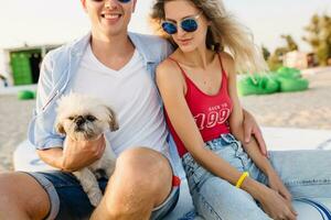 young attractive smiling couple having fun on beach playing with dogs photo