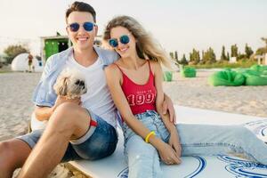 young attractive smiling couple having fun on beach playing with dogs photo