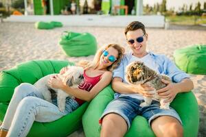 young attractive smiling couple having fun on beach playing with dogs photo