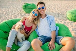 young attractive smiling couple having fun on beach playing with dogs photo