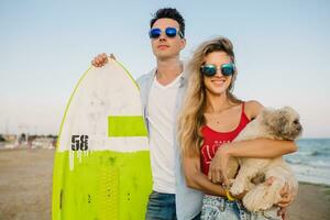 young attractive smiling couple having fun on beach playing with dogs photo