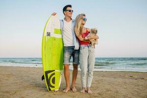 young attractive smiling couple having fun on beach playing with dogs photo