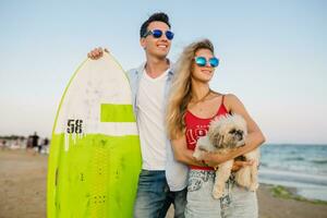 young attractive smiling couple having fun on beach playing with dogs photo