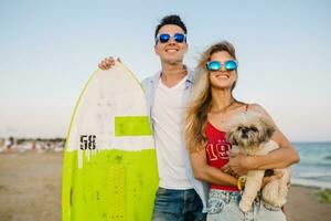 young attractive smiling couple having fun on beach playing with dogs photo