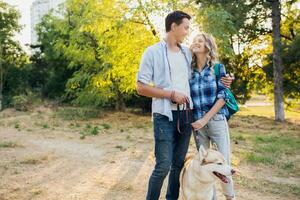 sunny young stylish couple playing with dog in park photo