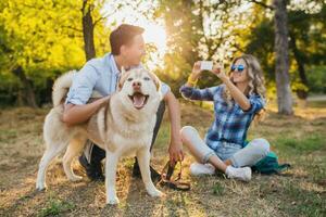 soleado joven elegante Pareja jugando con perro en parque foto