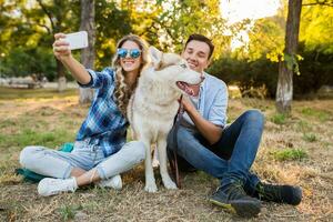 soleado joven elegante Pareja jugando con perro en parque foto