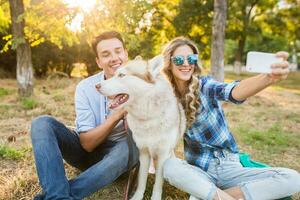 sunny young stylish couple playing with dog in park photo