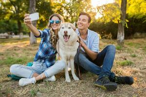 soleado joven elegante Pareja jugando con perro en parque foto