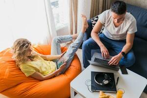 joven hombre y mujer en amor sentado a hogar trabajando en línea foto
