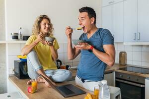 young attractive couple of man and woman cooking breakfast together in morning at kitchen photo