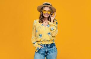 stylish happy smiling blond woman on vacation in straw on yellow background photo