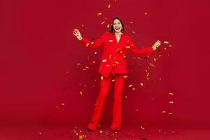 attractive woman celebrating Christmas on red background in confetti photo