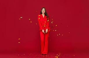 attractive woman celebrating Christmas on red background in confetti photo