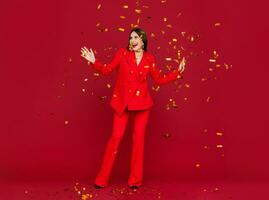 attractive woman celebrating Christmas on red background in confetti photo