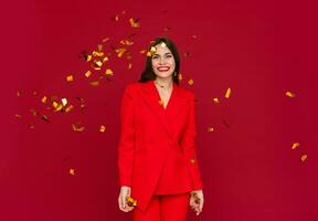 attractive woman celebrating Christmas on red background in confetti photo