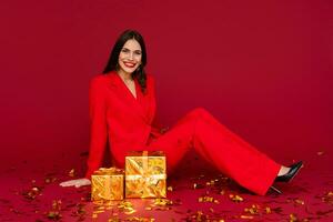 attractive woman celebrating Christmas on red background in confetti photo