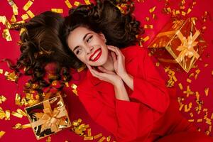 attractive woman celebrating Christmas on red background in confetti photo